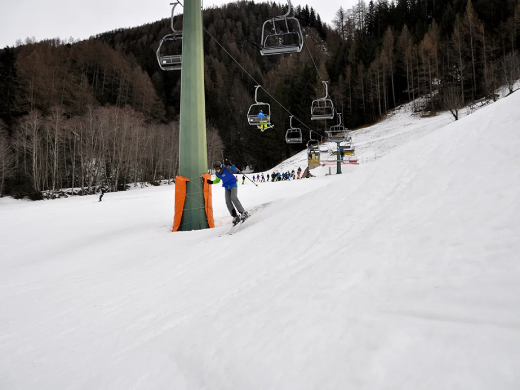 Snowboarder fährt an der Liftstütze vorbei.